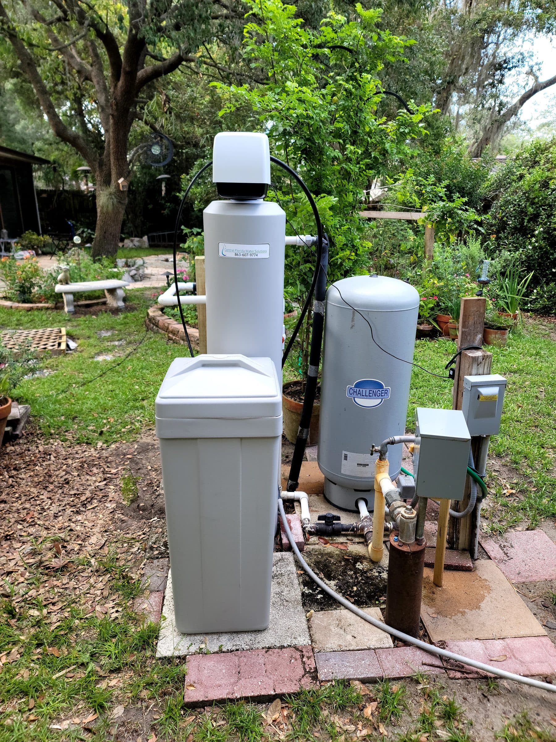 Cabinet softener and well pressure tank installed in a backyard garden